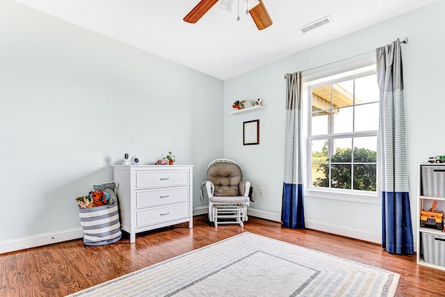 living area with visible vents, baseboards, wood finished floors, and a ceiling fan