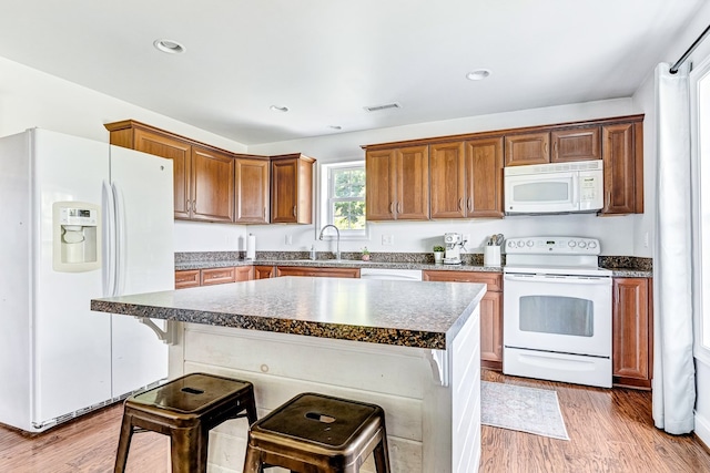 kitchen with visible vents, light wood-style flooring, white appliances, and a sink