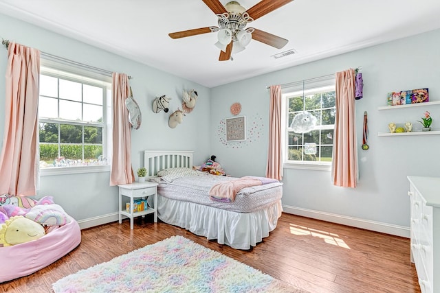 bedroom with multiple windows, baseboards, and wood finished floors