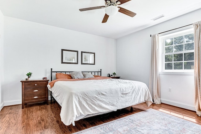 bedroom with visible vents, baseboards, wood finished floors, and a ceiling fan