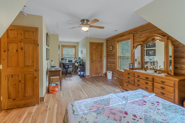 bedroom with wood walls, ceiling fan, and light hardwood / wood-style floors