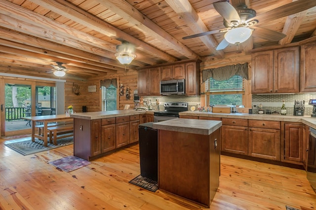 kitchen with appliances with stainless steel finishes, backsplash, light hardwood / wood-style flooring, beamed ceiling, and a kitchen island