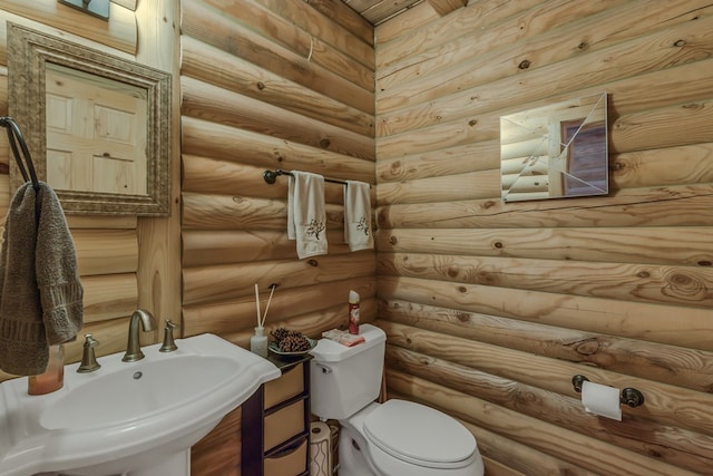 bathroom featuring sink, log walls, and toilet