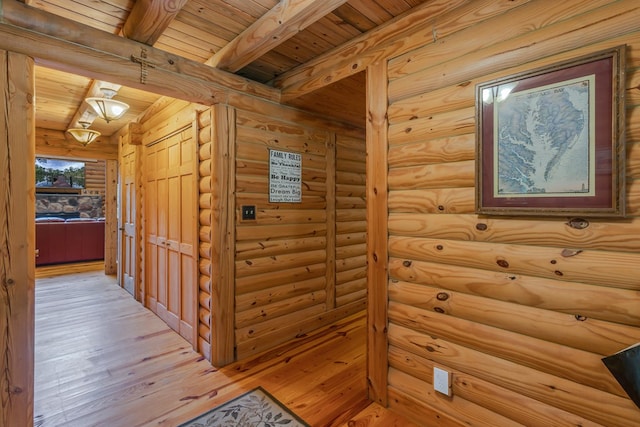 hallway with beamed ceiling, light hardwood / wood-style flooring, rustic walls, and wood ceiling