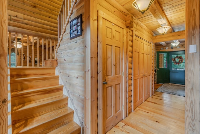 stairway featuring beam ceiling, rustic walls, hardwood / wood-style floors, and wooden ceiling