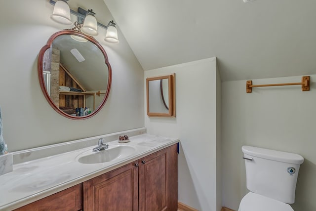 bathroom with toilet, vanity, and vaulted ceiling