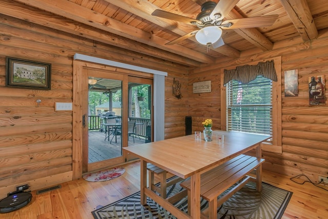 dining space featuring log walls, light hardwood / wood-style flooring, and beamed ceiling