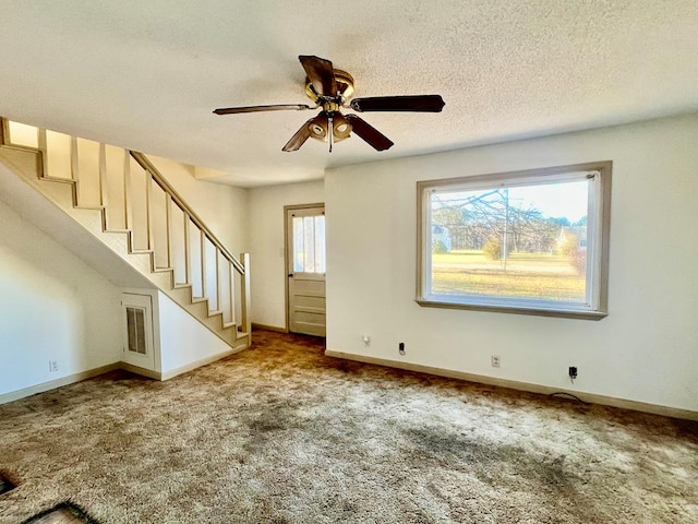 unfurnished living room featuring ceiling fan, light colored carpet, and a textured ceiling