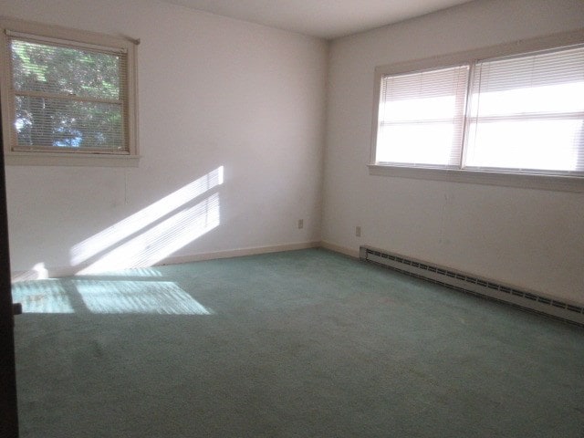 carpeted empty room featuring plenty of natural light and a baseboard heating unit