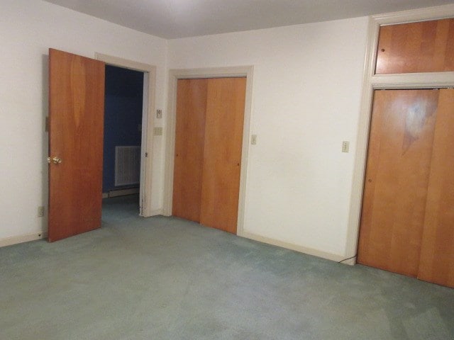 unfurnished bedroom featuring radiator heating unit, light carpet, and a closet