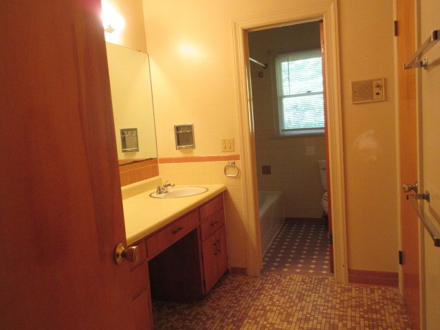 bathroom featuring tile patterned floors, vanity, toilet, and tile walls