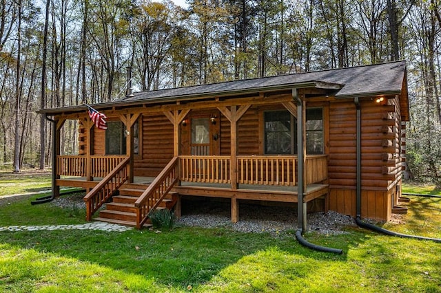 cabin featuring a front yard, a porch, and log siding
