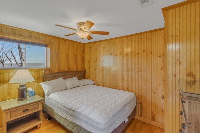 bedroom with wood walls, ornamental molding, wood-type flooring, and ceiling fan