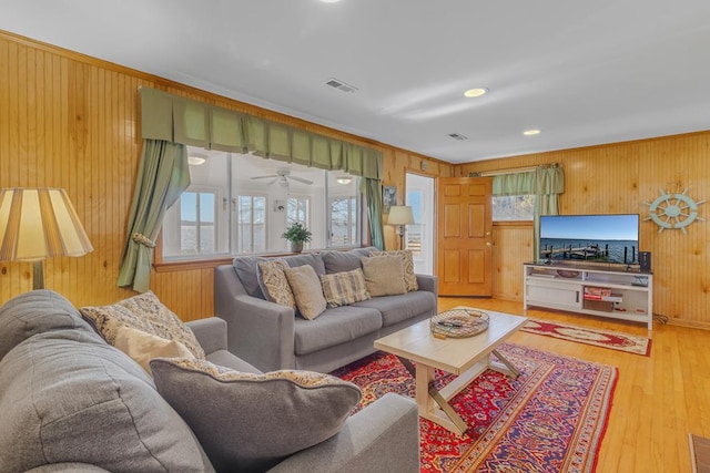 living room with hardwood / wood-style floors, wooden walls, and a healthy amount of sunlight