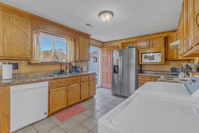 kitchen featuring exhaust hood, washer and dryer, white appliances, light tile patterned floors, and sink