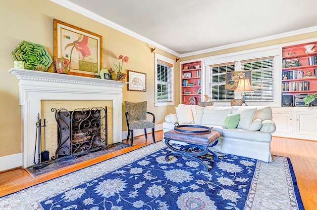 living room with built in shelves, a brick fireplace, crown molding, and wood-type flooring