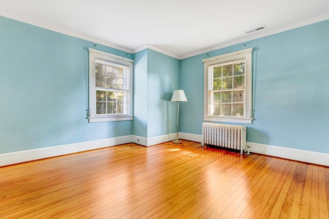 unfurnished room with hardwood / wood-style floors, crown molding, and radiator