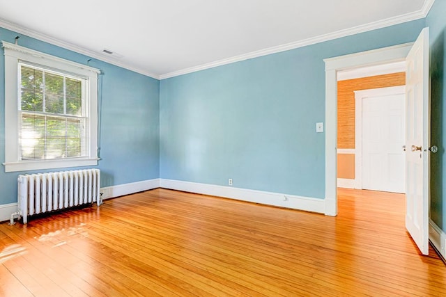 empty room featuring light wood-type flooring, radiator, and ornamental molding