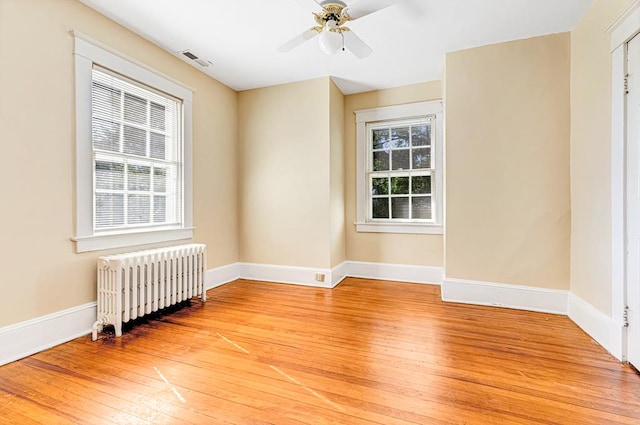 unfurnished room featuring radiator, ceiling fan, plenty of natural light, and light wood-type flooring