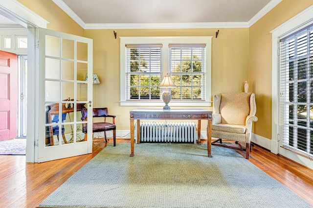 living area with radiator, hardwood / wood-style flooring, french doors, and ornamental molding