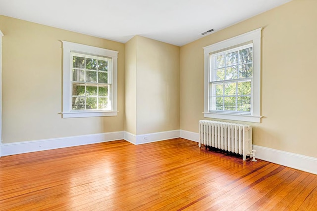 spare room featuring radiator and light hardwood / wood-style flooring