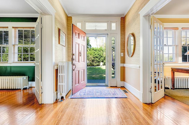 foyer entrance featuring light hardwood / wood-style floors, radiator, and crown molding