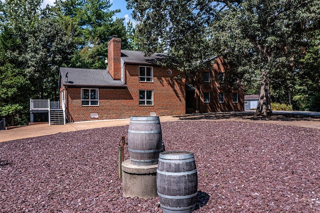view of side of property featuring a chimney, crawl space, brick siding, a deck, and a shingled roof