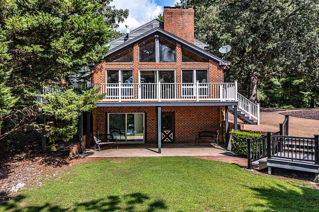 back of property with a chimney, a patio, a yard, and brick siding