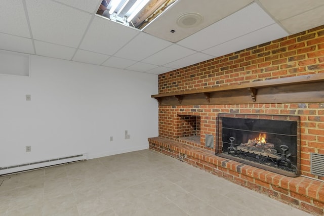 unfurnished living room with a baseboard radiator, baseboards, a drop ceiling, and a brick fireplace