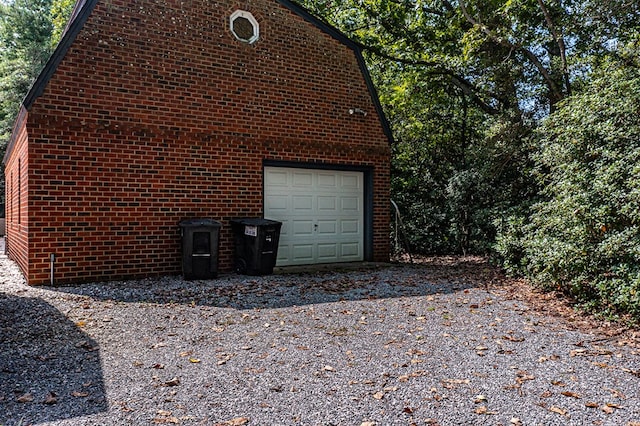 view of side of home featuring a garage, an outdoor structure, and brick siding