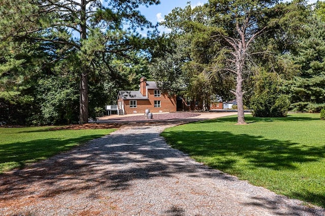 exterior space featuring a front yard, gravel driveway, and a chimney