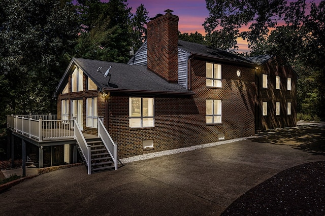 exterior space with stairway, a patio, brick siding, a chimney, and driveway