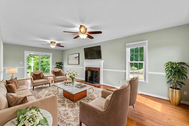 living room featuring a brick fireplace, light hardwood / wood-style flooring, and ceiling fan