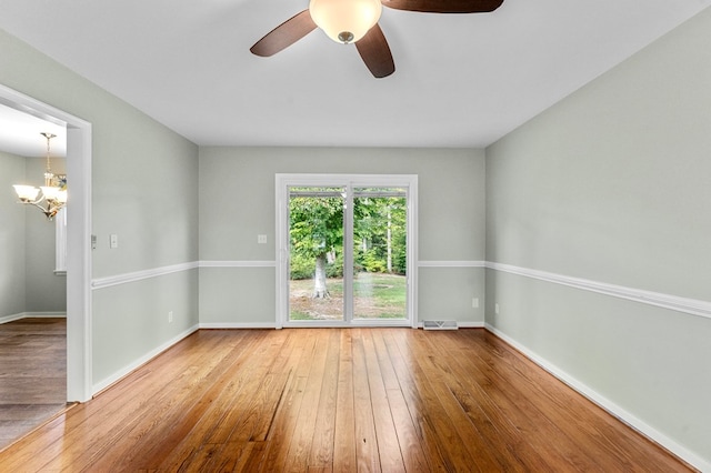 empty room featuring hardwood / wood-style flooring and ceiling fan with notable chandelier