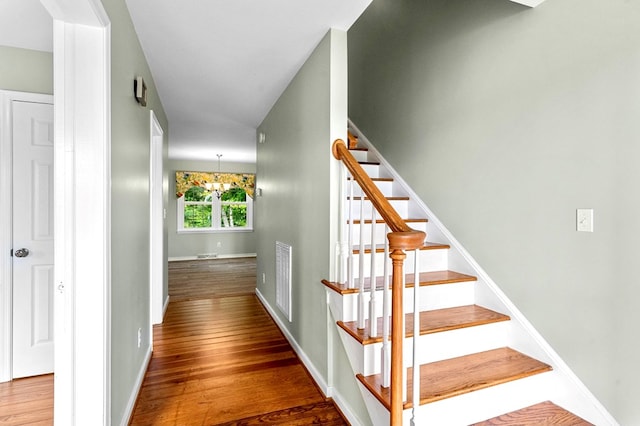 staircase featuring hardwood / wood-style flooring and a chandelier