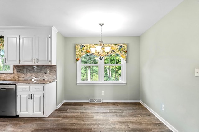 unfurnished dining area with an inviting chandelier, plenty of natural light, and dark hardwood / wood-style floors