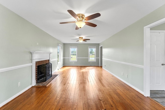 unfurnished living room featuring wood-type flooring and a brick fireplace