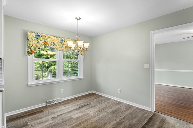 empty room featuring wood-type flooring and a chandelier