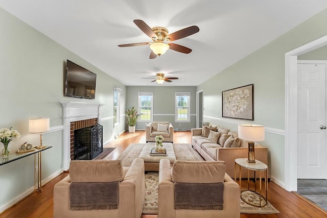 living room featuring ceiling fan, hardwood / wood-style floors, and a fireplace