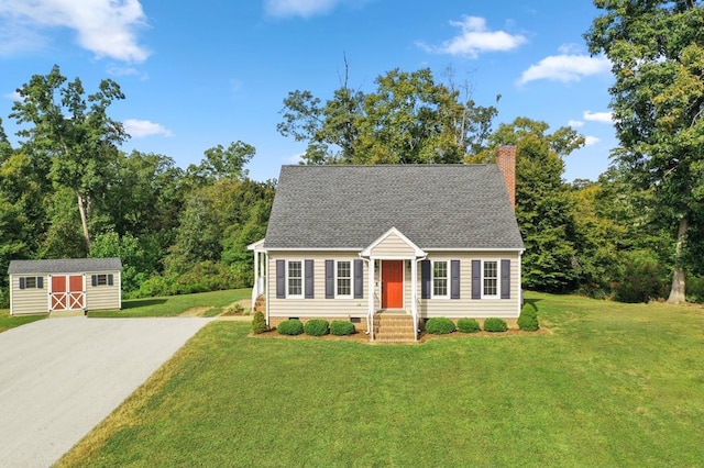 cape cod house with a front yard and a storage unit