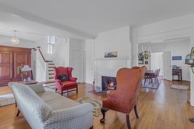 living room featuring a chandelier, beam ceiling, and light hardwood / wood-style floors