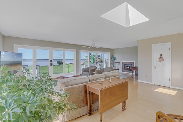 living room featuring light wood-type flooring, a skylight, and ceiling fan