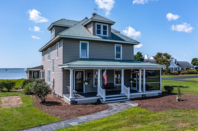 view of front of home featuring covered porch, a water view, and a front lawn