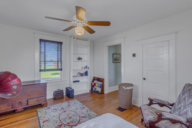 sitting room with ceiling fan and wood-type flooring