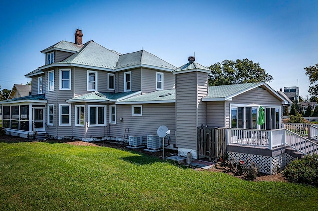 rear view of house with a lawn, a wooden deck, a sunroom, and cooling unit