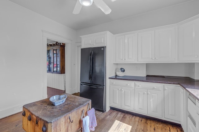 kitchen with ceiling fan, black fridge, white cabinets, and light wood-type flooring