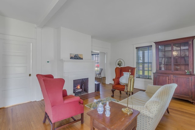 living room featuring beam ceiling and light hardwood / wood-style flooring