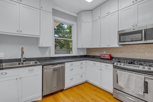 19 Cedardale Ln, Irvington, VA 22480 - kitchen featuring appliances with stainless steel finishes, white cabinets, light wood finished floors, dark countertops, and backsplash