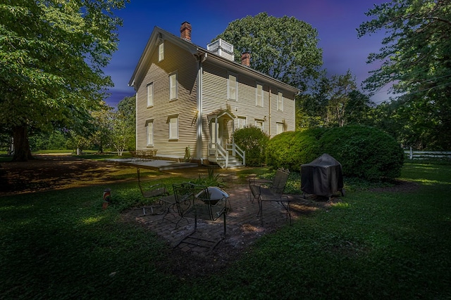 19 Cedardale Ln, Irvington, VA 22480 - back of property at dusk with a chimney, a yard, and a patio area