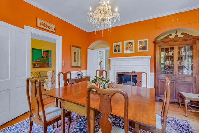 19 Cedardale Ln, Irvington, VA 22480 - dining room featuring light wood-type flooring, a chandelier, crown molding, a fireplace, and arched walkways